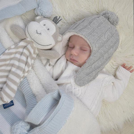 beautiful baby sleeping with a blue knitted winter blanket and knitted monkey toy
