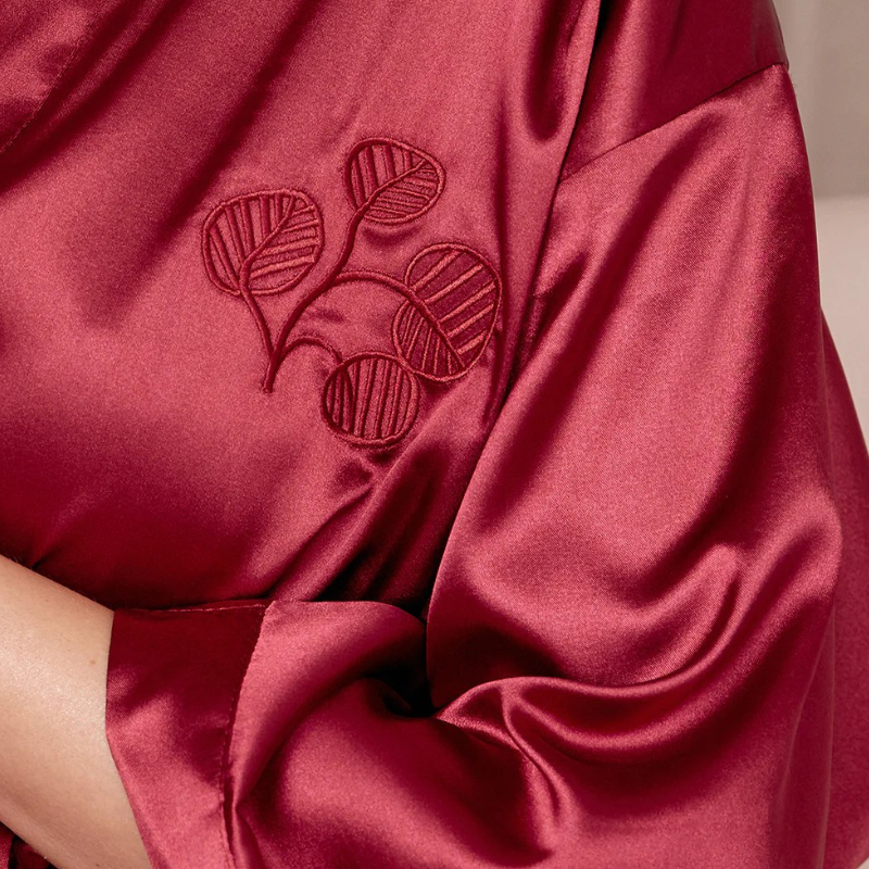 Close-up of a red satin robe with leaf embroidery.