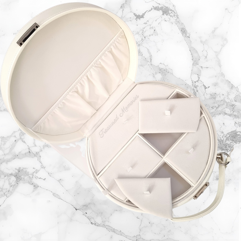 Round beige keepsake case with compartments to store memorable items sitting on a marble surface