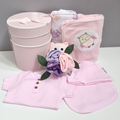 Baby owl design clothing and accessories set with pink hat, onsie, and blankets on a white surface.