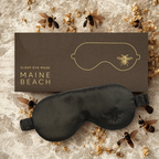 Sleep eye mask with 'Maine Beach' branding on a textured surface with bee decorations.