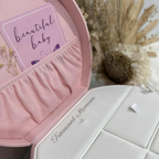 Pink jewelry keepsake box with 'beautiful baby' card and 'Treasured Memories' text on a white surface.