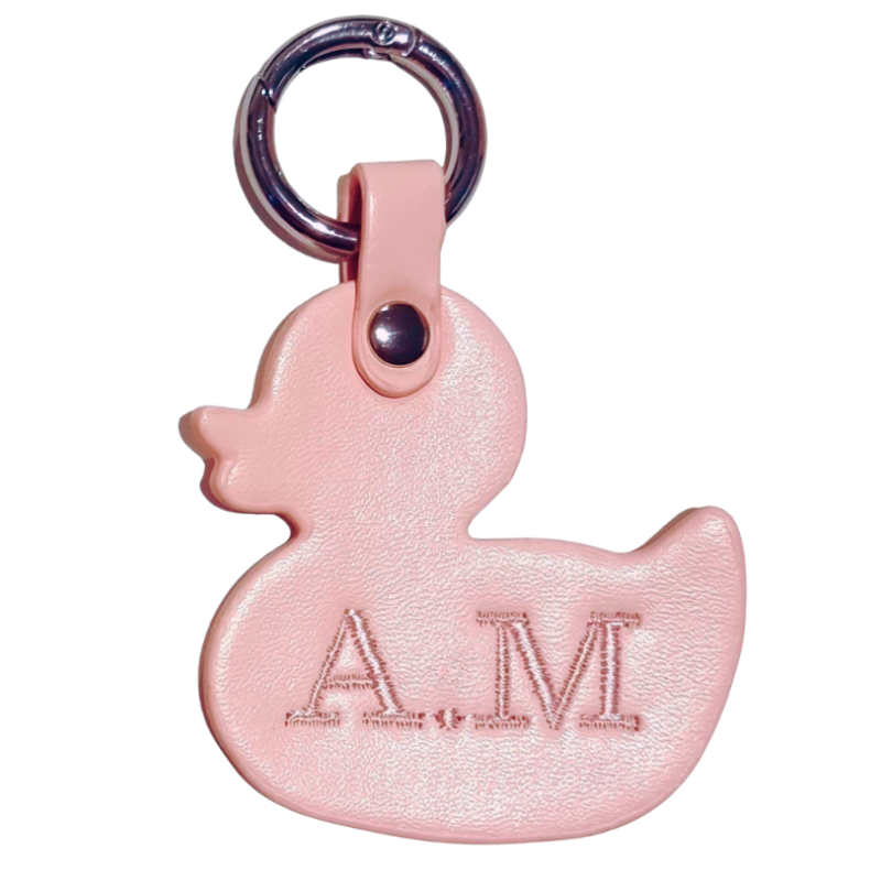 Pink duck-shaped keychain with 'AM' initials embroidered on a white background