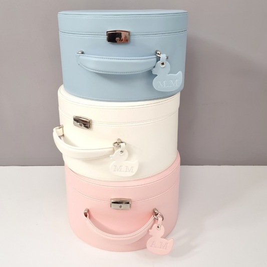 Stack of three pastel-colored cylindrical suitcases on a white surface with a gray background