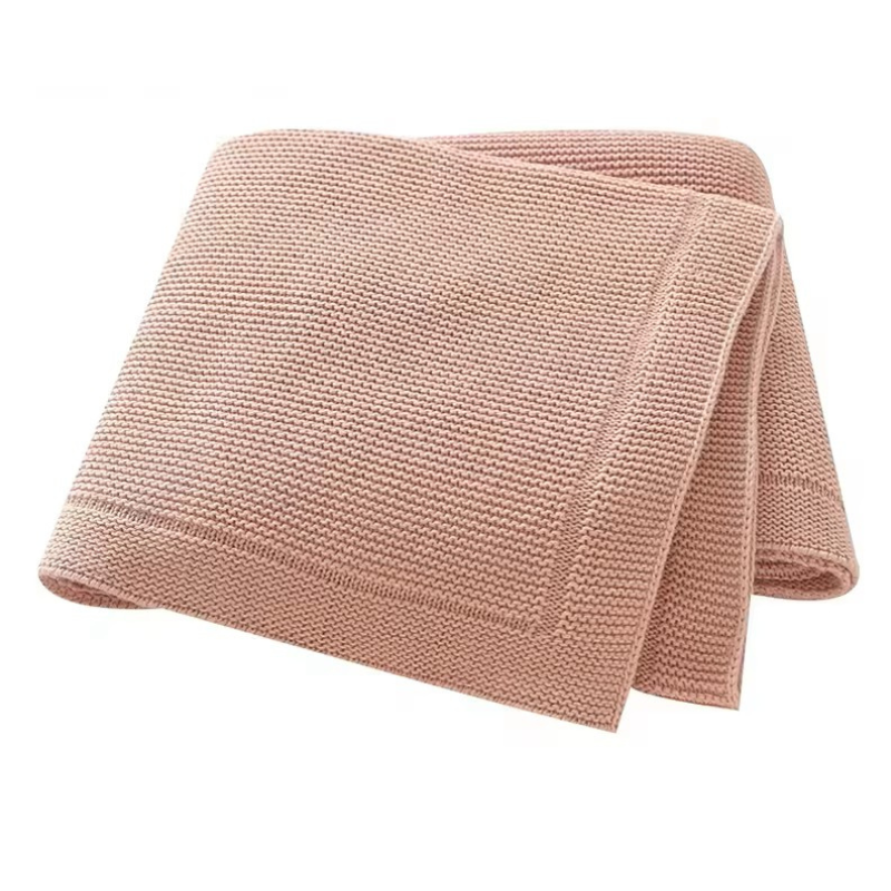 A folded rose pink knitted baby blanket with a solid line bordered edge, displayed on a white background