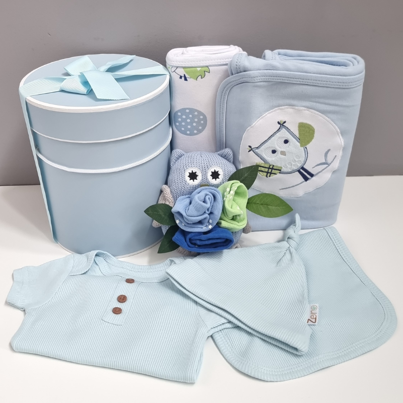 Collection of baby items including a onsie, blanket, and various accessories on a white surface.