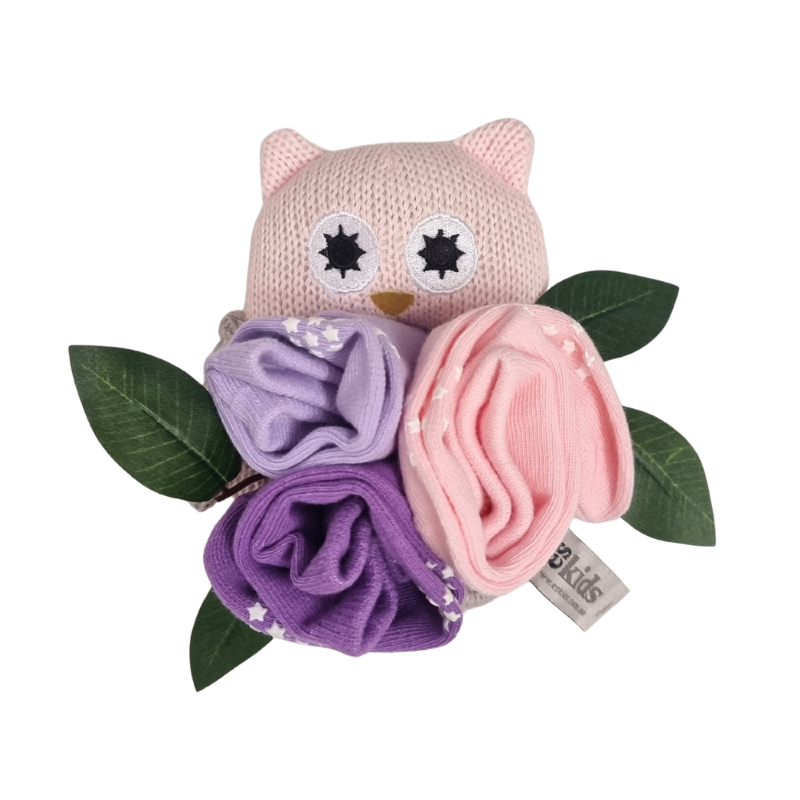 Pink owl-shaped toy with purple and pink baby sock flowers on a white background