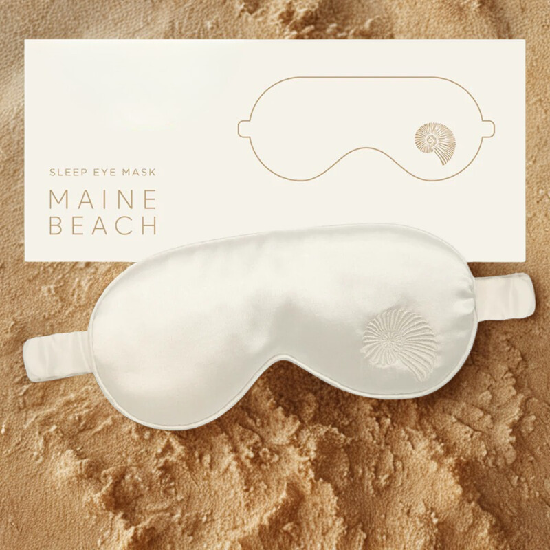 Silk sleep eye mask with 'Maine Beach' branding on a sandy background