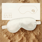 Silk sleep eye mask with 'Maine Beach' branding on a sandy background