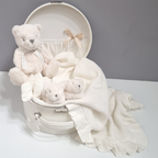 White teddy bear and baby blankets in a suitcase on a gray background