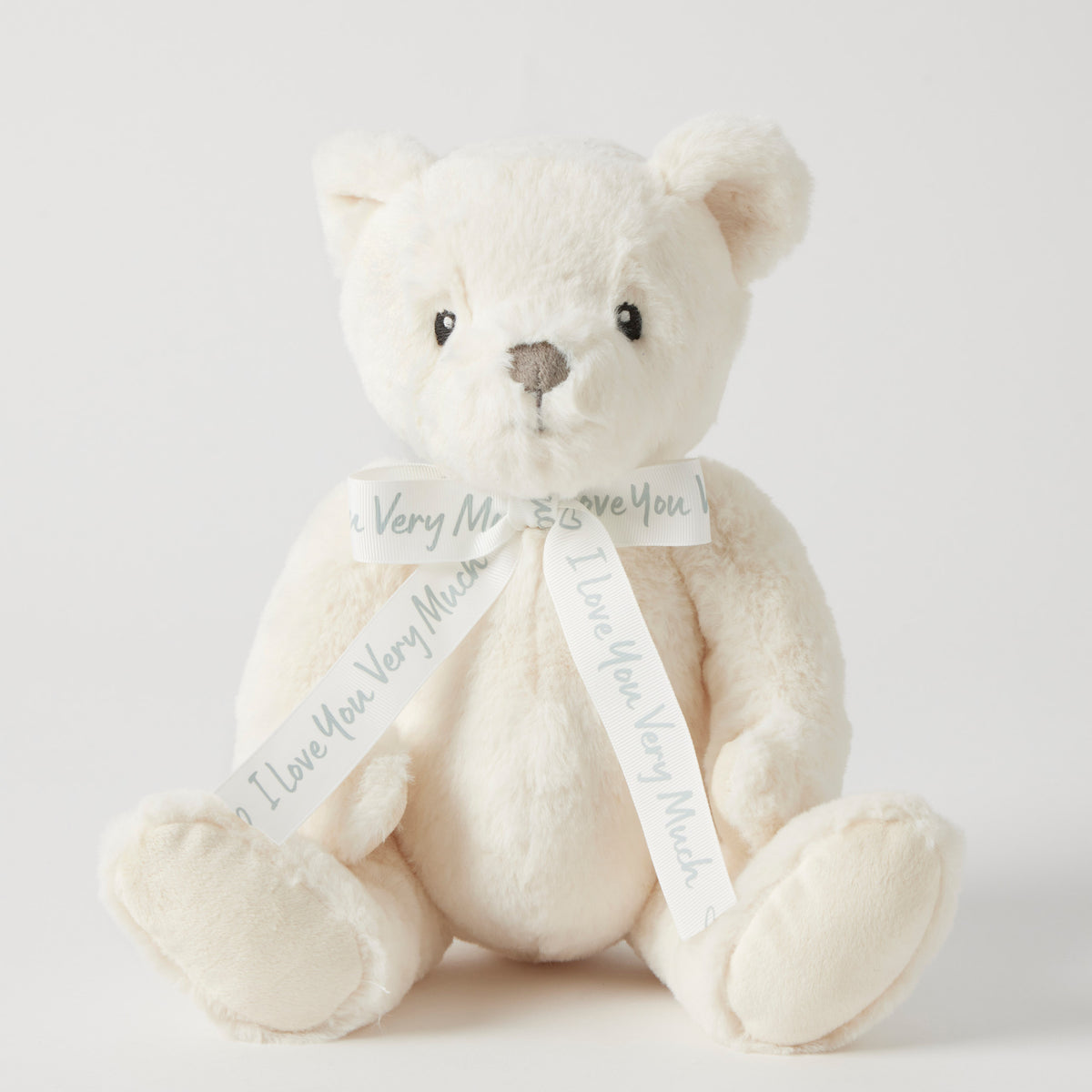 White teddy bear with a ribbon on a light gray background