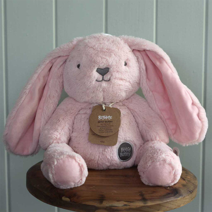 large pink bunny soft toy sitting on stool
