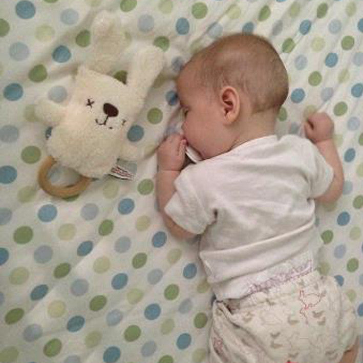 baby sleeping with neutral cream bunny baby rattle