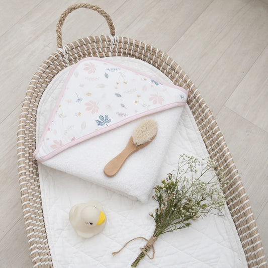 Organic Muslin pink hooded towel with botanical leaf design in basket.