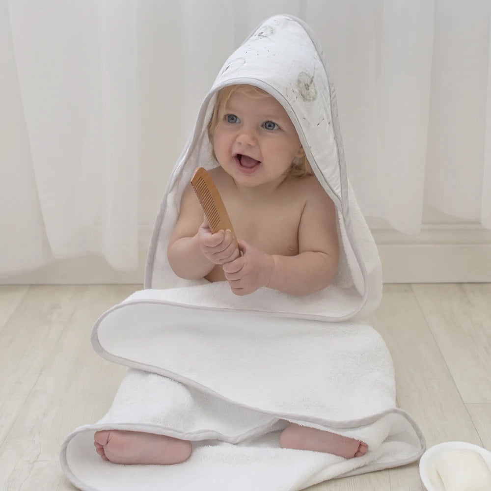 baby wearing Organic Muslin grey hooded towel with dandelion design.